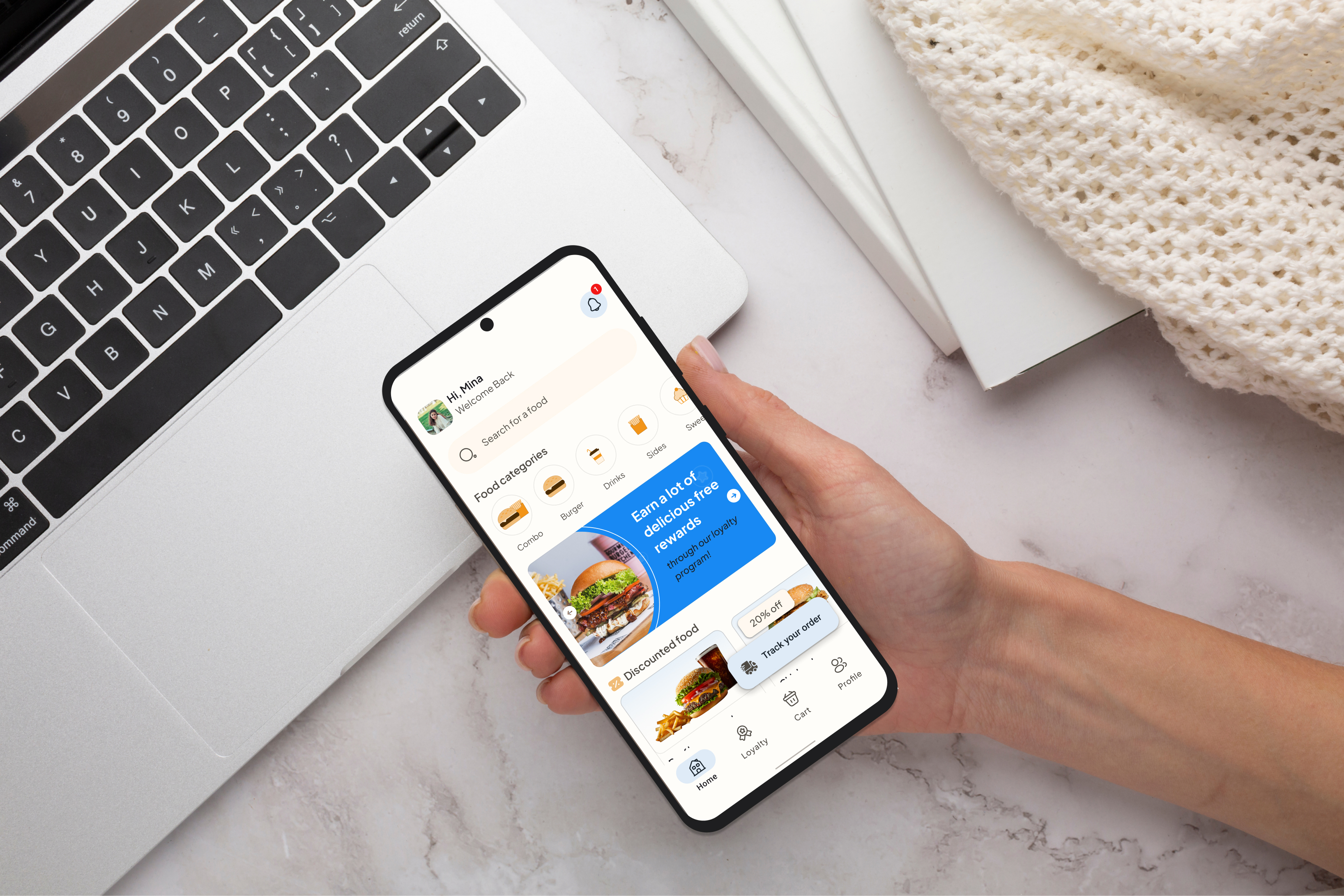 Burgermania app shown on a phone held in hand